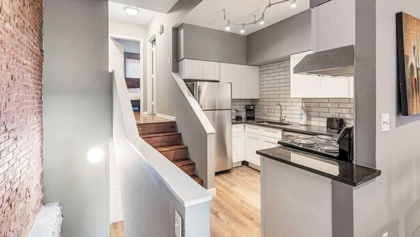 Una cocina moderna con una isla central, electrodomésticos de acero inoxidable y una pared de ladrillo decorativa.