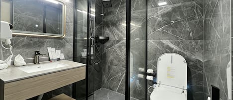 A modern bathroom with a glass-enclosed shower, a white sink, and a toilet.