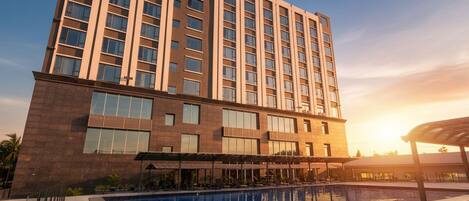 A modern hotel with a large pool and a sunset view.