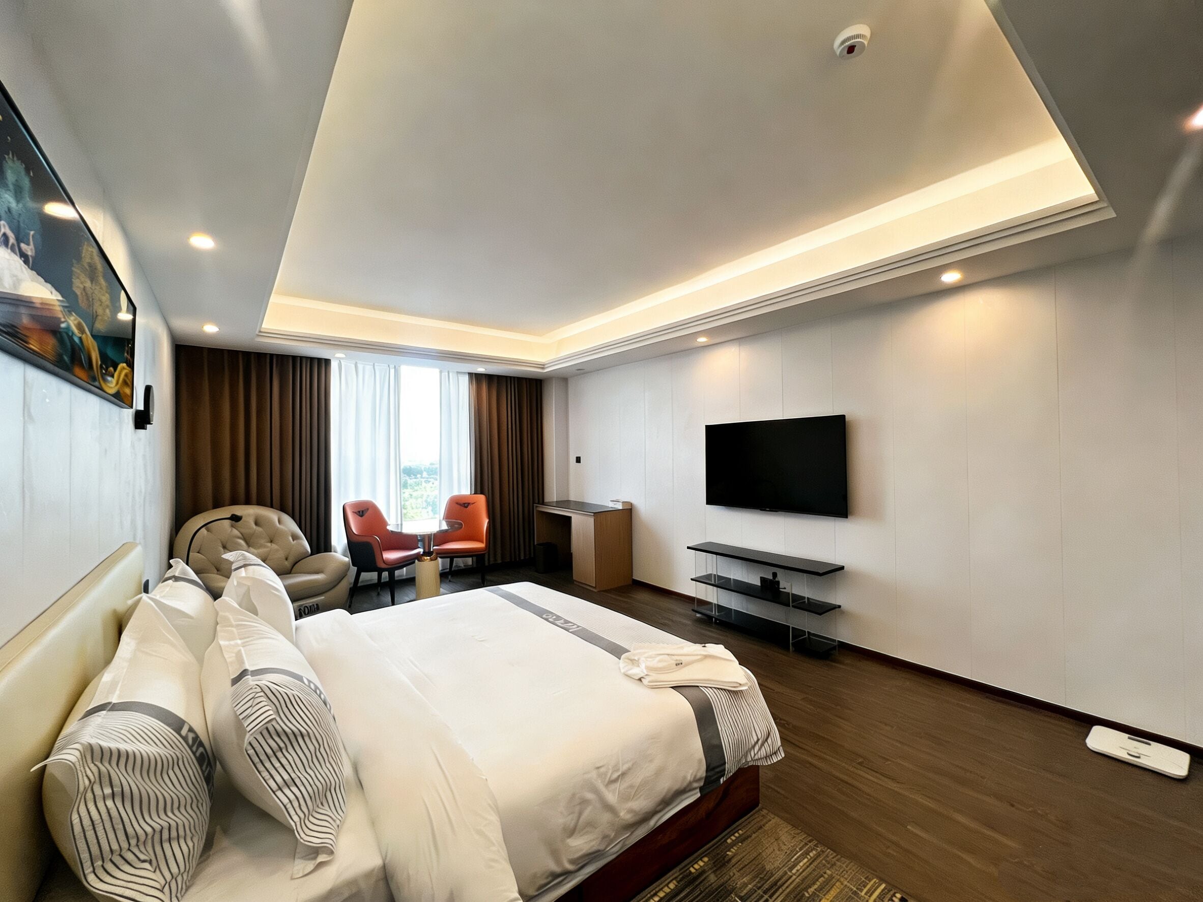 Una habitación de hotel moderna con una cama grande, un escritorio, un televisor y dos sillas.