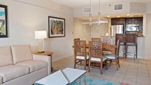 Un salon comprenant un canapé, une table basse et un coin repas avec des chaises et une table. Il y a également une cuisine équipée de placards et d’un four à micro-ondes.