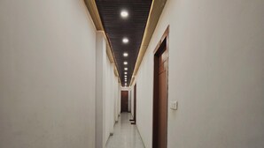 Un pasillo largo y estrecho con paredes blancas y un suelo moteado.