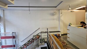 Un vestíbulo de hotel con una escalera, una recepción y un ventilador de techo.