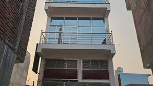 Un edificio de varios pisos con techo plano, ventanas grandes y una reja metálica en la entrada.