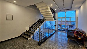 Un interior amplio con una escalera moderna, un gran ventanal con vistas y un piso limpio y pulido.