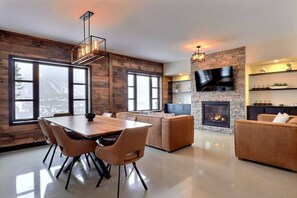 Ein modernes Wohnzimmer mit Kamin, Essbereich und Wand-Fernseher.