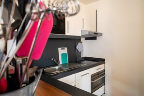 Eine moderne Küche mit schwarzem Arbeitsplatz, Spüle aus Edelstahl, weißen Schränken und einer Siemens-Mikrowelle.