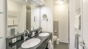 Un baño moderno con dos lavamanos, un espejo grande y un inodoro.