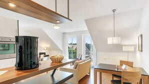 Una cocina moderna con cafetera, un comedor con mesa y sillas, y un sofá.