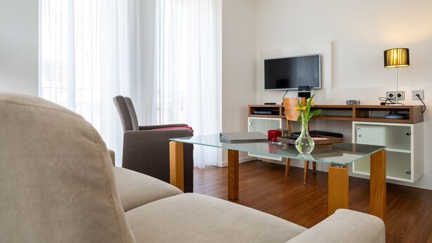 A modern living room with a glass coffee table, a flat-screen TV mounted on the wall, a lamp, and a sofa. - 5-Star Comfort Holiday Home Jümmers: 'Trientje', Prime Location by Wadden Sea National Park (Wangerland-Horumersiel)