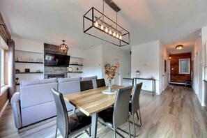 A modern dining area with a wooden table and chairs, a built-in bench, and a pendant light. - Condos Monts-Valin -161, rue du Massif (Valinouët) (Saint-David-de-Falardeau)