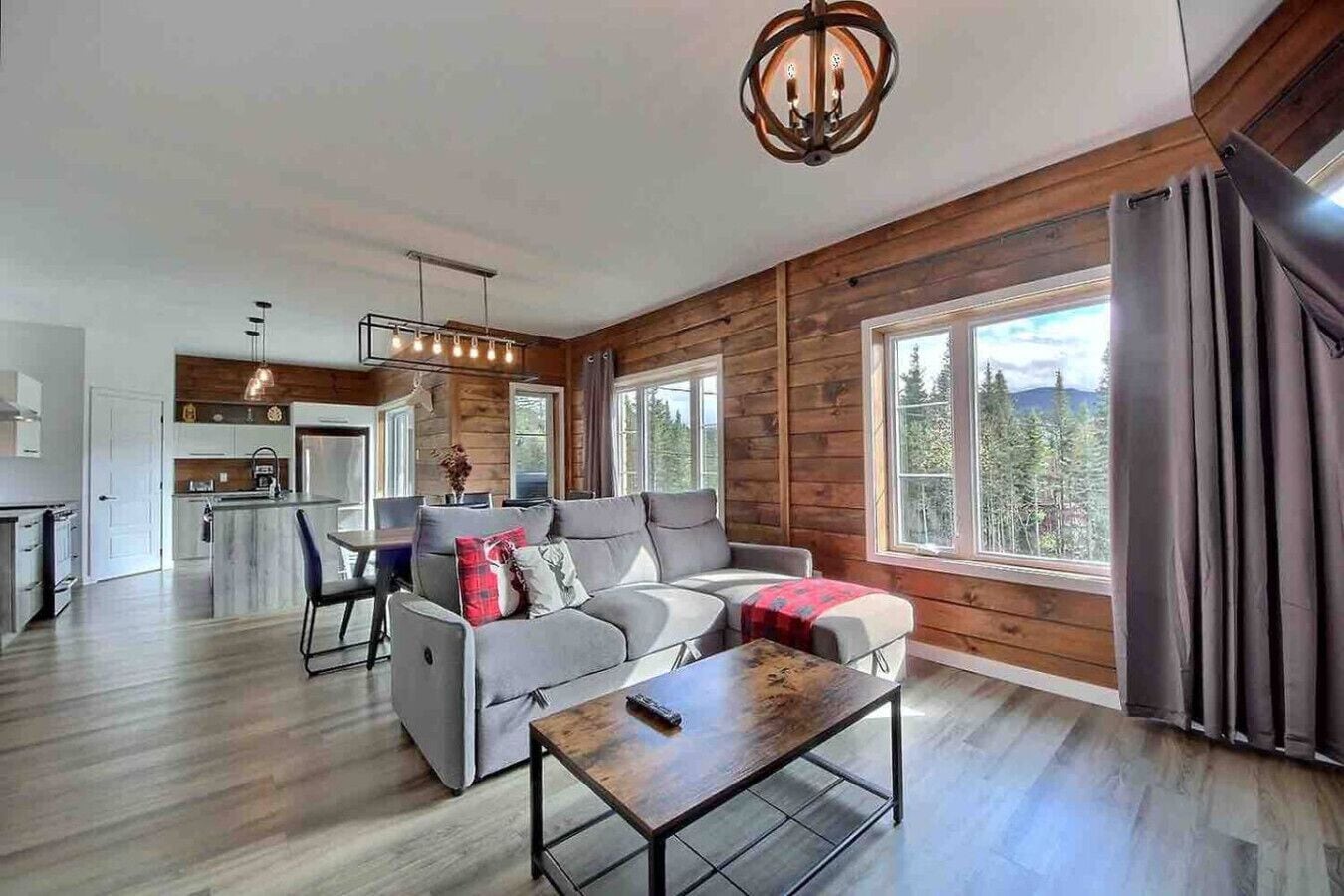 A modern living room with a grey sofa, a coffee table, and a dining area with a table and chairs.