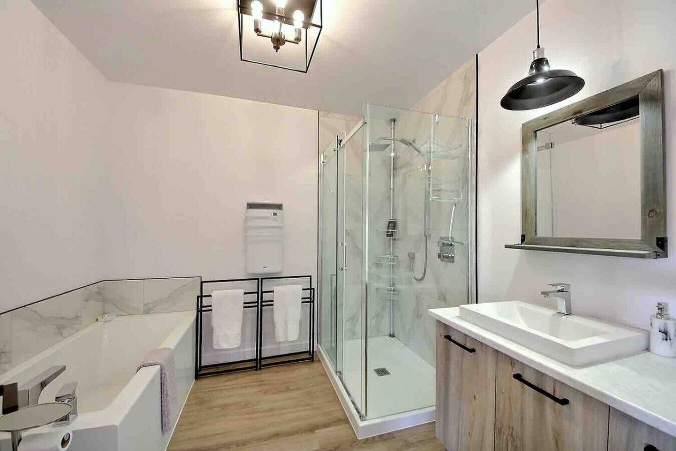 Un baño moderno con ducha de vidrio, bañera independiente y tocador con espejo.