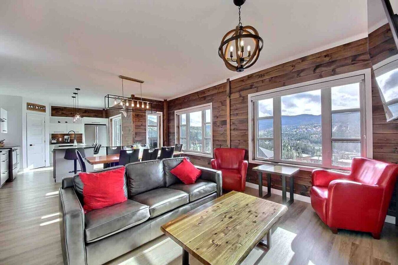 A modern living room with a sofa, red chairs, and a wooden coffee table.