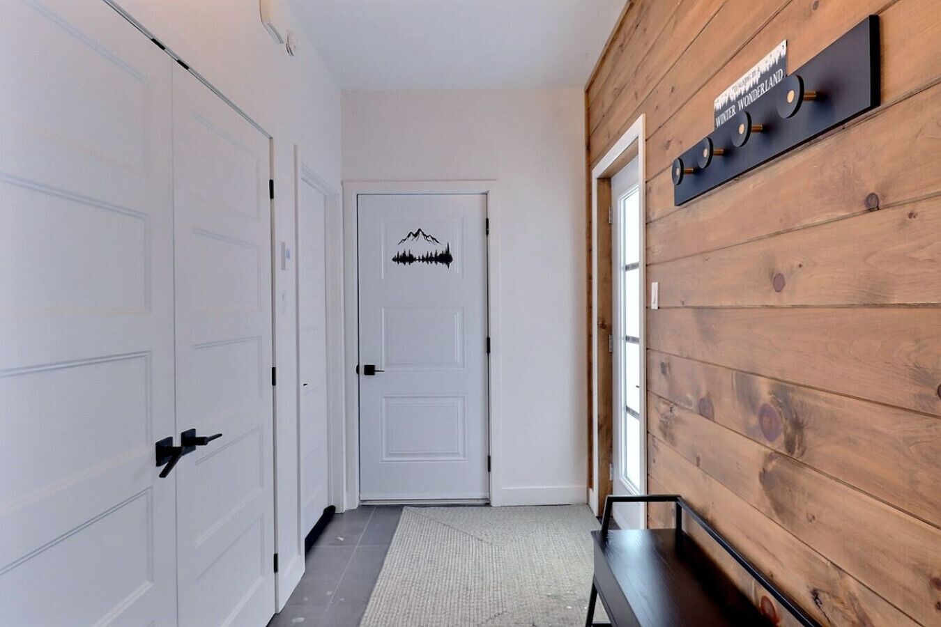 Un pasillo con puertas blancas, un muro de madera y un letrero que dice 'Winter Wonderland'.
