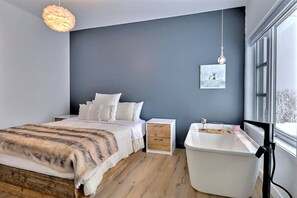 Ein modernes Schlafzimmer mit Bett, Nachttisch und einem großen Fenster.