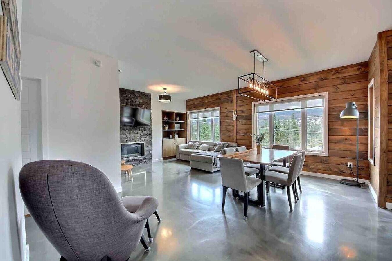 Un'ampia zona giorno con cucina moderna, tavolo da pranzo e una grande finestra vista all'esterno.