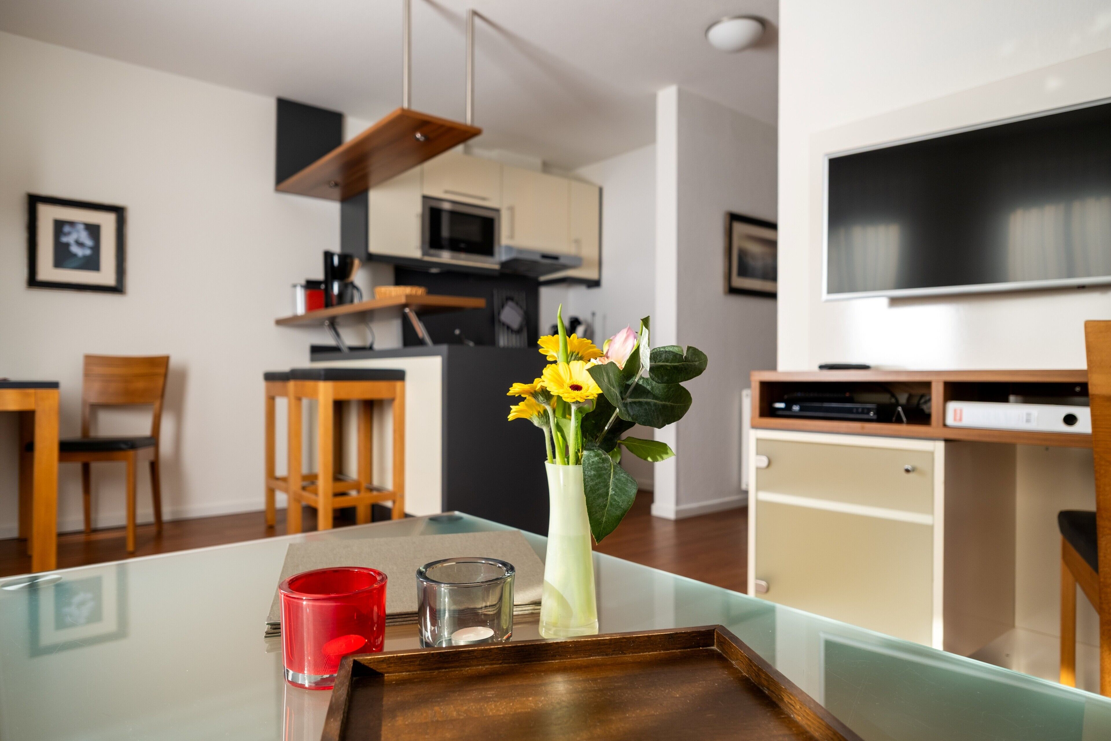 Eine moderne Küche mit Mikrowelle, ein Essbereich mit Stühlen und einem Fernseher an der Wand.