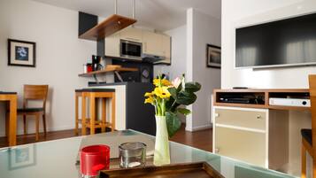 Eine moderne Küche mit Mikrowelle, ein Essbereich mit Stühlen und einem Fernseher an der Wand.