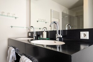 Un baño moderno con dos lavamanos, un espejo grande y estantes de vidrio.