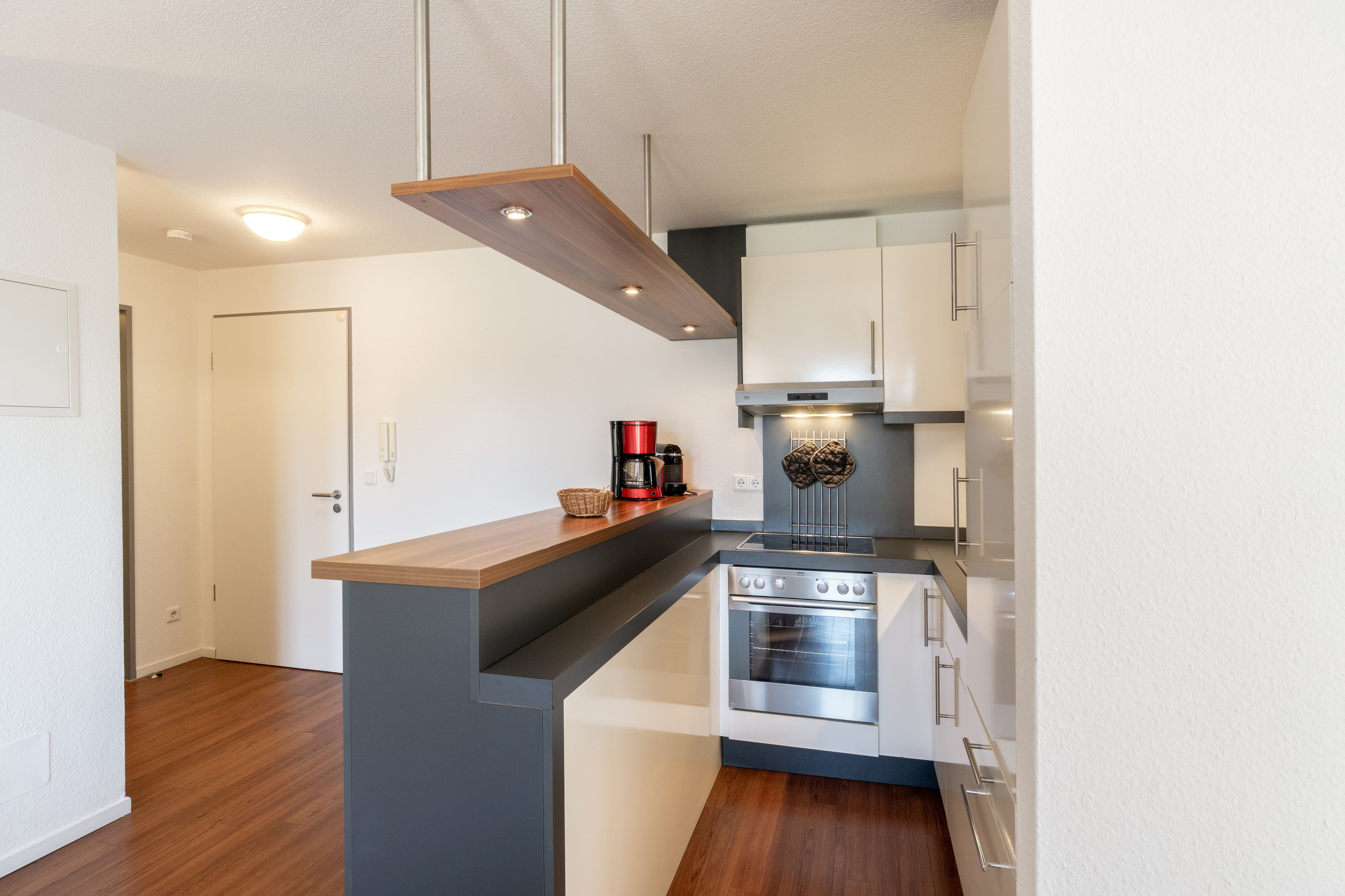 Eine moderne Küche mit Backofen, Kaffeemaschine und einer abgehängten Kochutensilienstange.