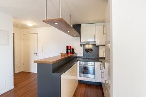 Eine moderne Küche mit Backofen, Kaffeemaschine und einer abgehängten Kochutensilienstange.