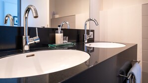 Une salle de bain moderne avec deux lavabos, un grand miroir et un porte-serviettes.