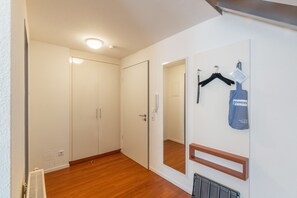 A hallway with a wooden floor, white walls, a door with a mirror, and a hanging item with text. - 5-Star Comfort Holiday Home Jümmers - 'Niklas', Prime Location by the Wadden Sea National Park (Wangerland-Horumersiel)
