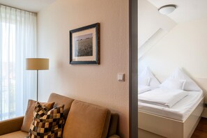 A hotel room with a bed, a sofa, a lamp, a framed picture on the wall, and a ceiling light. - 5-Star Comfort Holiday Home Jümmers - 'Niklas', Prime Location by the Wadden Sea National Park (Wangerland-Horumersiel)