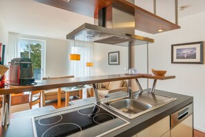 A modern kitchen with a built-in stove, stainless steel sink, and a wooden countertop. - 5-Star Comfort Holiday Home Jümmers - 'Niklas', Prime Location by the Wadden Sea National Park (Wangerland-Horumersiel)
