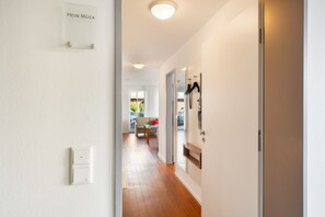 A hallway with a clear view into a living area, a door labeled 'HEIN MÜCK', and a coat rack with items hanging. - 5-Star Comfort Holiday Home Jümmers: 'Hein Mück', Prime Location by the Wadden Sea National Park (Wangerland-Horumersiel)