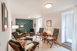 A well-lit living room with a modern design, featuring a patterned wall, multiple seating options, and a large window providing natural light. - 5-Star Comfort Holiday Home Jümmers: 'Hein Mück', Prime Location by the Wadden Sea National Park (Wangerland-Horumersiel)