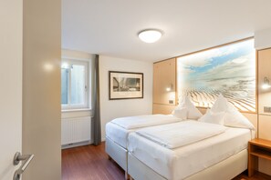 Habitación de hotel con una cama doble, un cuadro en la pared, una ventana y un radiador.