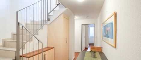 A modern interior with a staircase, a dining area, and a hallway leading to another room.