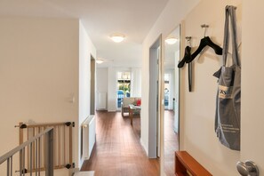 Un couloir avec un escalier en bois, un radiateur et un banc.