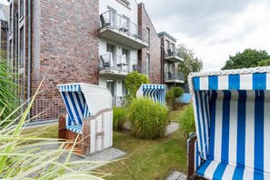 A residential building with brick walls, a small garden, and outdoor seating with striped cushions. - 5-Star Comfort Holiday Home Jümmers: 'Hein Mück', Prime Location by the Wadden Sea National Park (Wangerland-Horumersiel)
