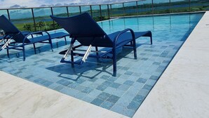 Zona de piscina con sillas de descanso y vista al paisaje.