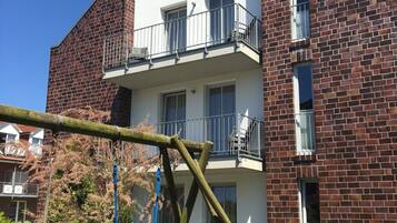 Ein zweigeschossiges Gebäude mit Ziegelverkleidung, einem Balkon im oberen Stockwerk und einer Schaukel im Vordergrund.