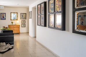 A hallway with framed artwork, a wooden dresser, and a black sofa. - 5-Star Comfort Holiday Home Jümmers - 'Sönke', Prime Location by the Wadden Sea National Park (Wangerland-Horumersiel)