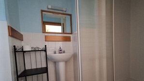 A bathroom with a sink, mirror, and shower. - The Albert Hotel (Gloucester)