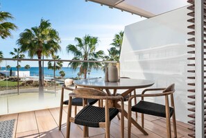 A balcony with a round table and four chairs, overlooking a pool and palm trees with a view of the ocean. - Casa Costa Tropical (Estepona)