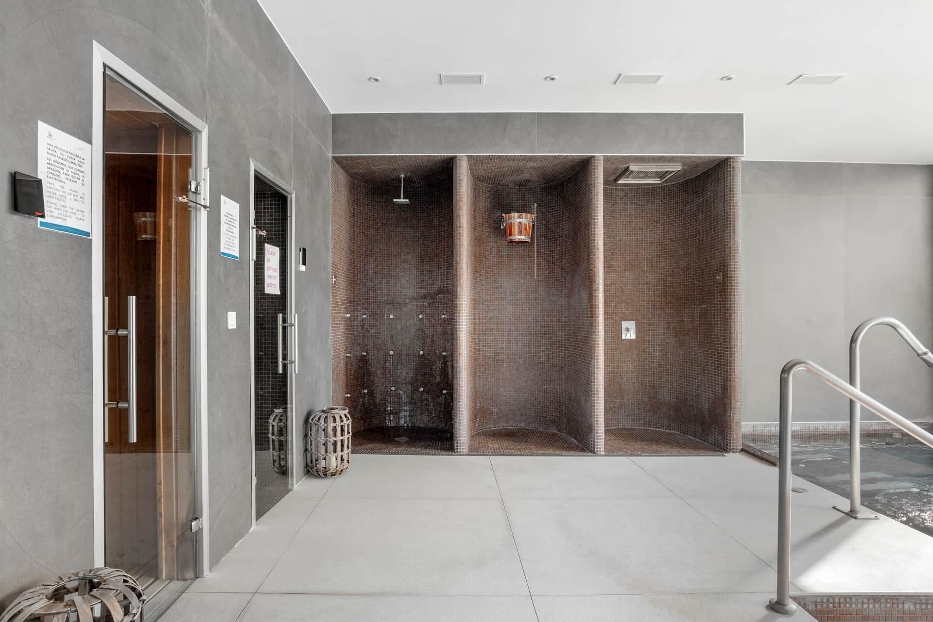 A modern bathroom with a glass shower enclosure, a towel rack, and a sign indicating a service area.