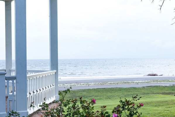 A covered porch with a view of the ocean.