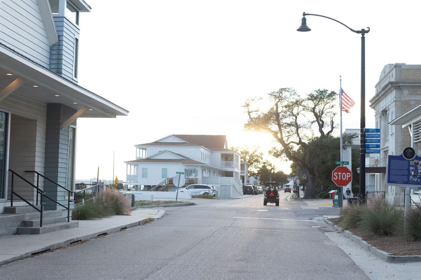 A street view with a stop sign, a signboard listing local businesses, and a building with a staircase.