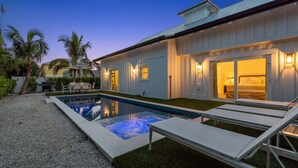 A modern house with a swimming pool, outdoor seating, and a well-lit entrance. - Honey I'm Holmes - New Home Near the Beach! Turf (Holmes Beach)