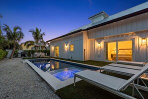 A modern house with a swimming pool, outdoor seating, and a well-lit entrance. - Honey I'm Holmes - New Home Near the Beach! Turf (Holmes Beach)