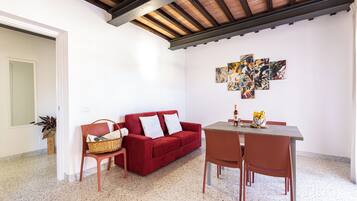 A living area with a red sofa, a wooden dining table, and a modern abstract art piece on the wall.