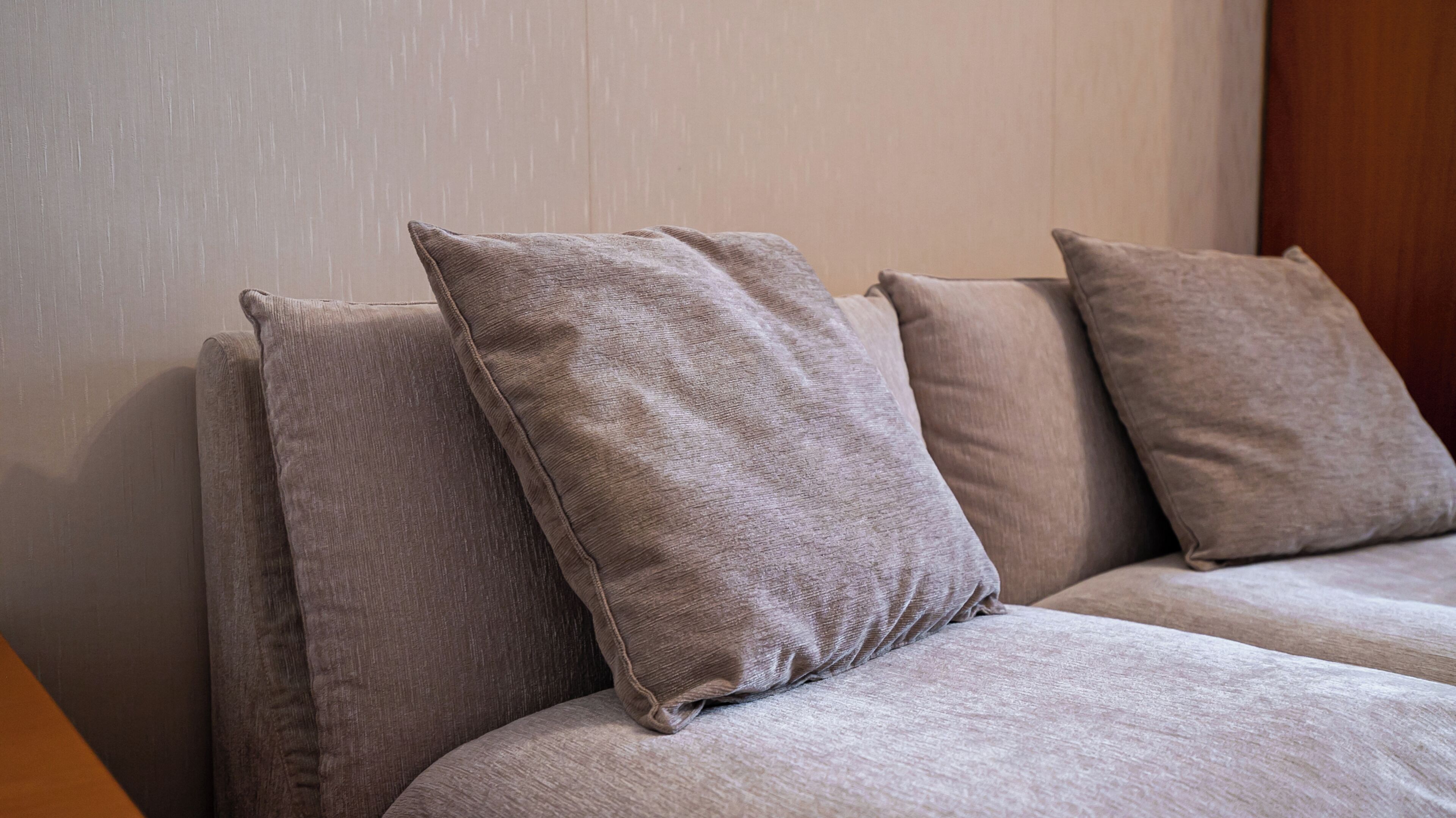 A sofa with three cushions against a wall.