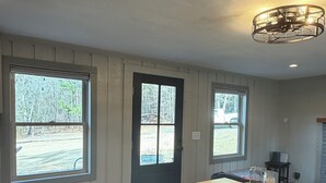 Cocina con suelo de madera, una isla central y dos ventanas con vista a árboles.