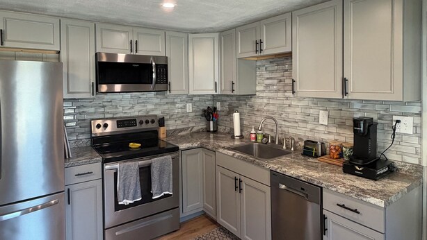 Una cocina moderna con electrodomésticos de acero inoxidable, armarios de gris claro y un salpicadero decorado.